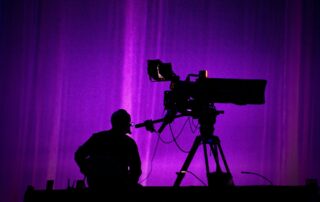 Multicam expertise – TV cameraman silhouette behind broadcast camera on stage