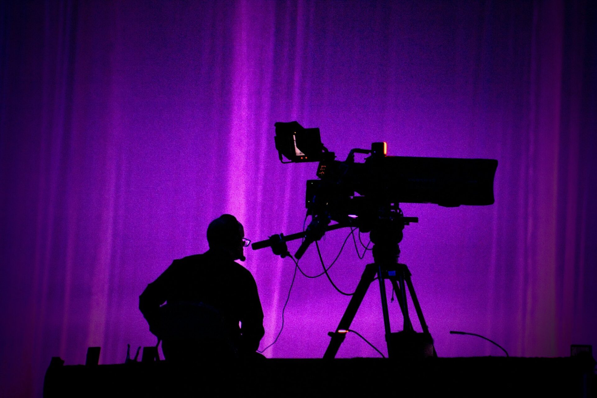 Multicam Expertise 1 - CINEWOLF media productions Multicam expertise – TV cameraman silhouette behind broadcast camera on stage